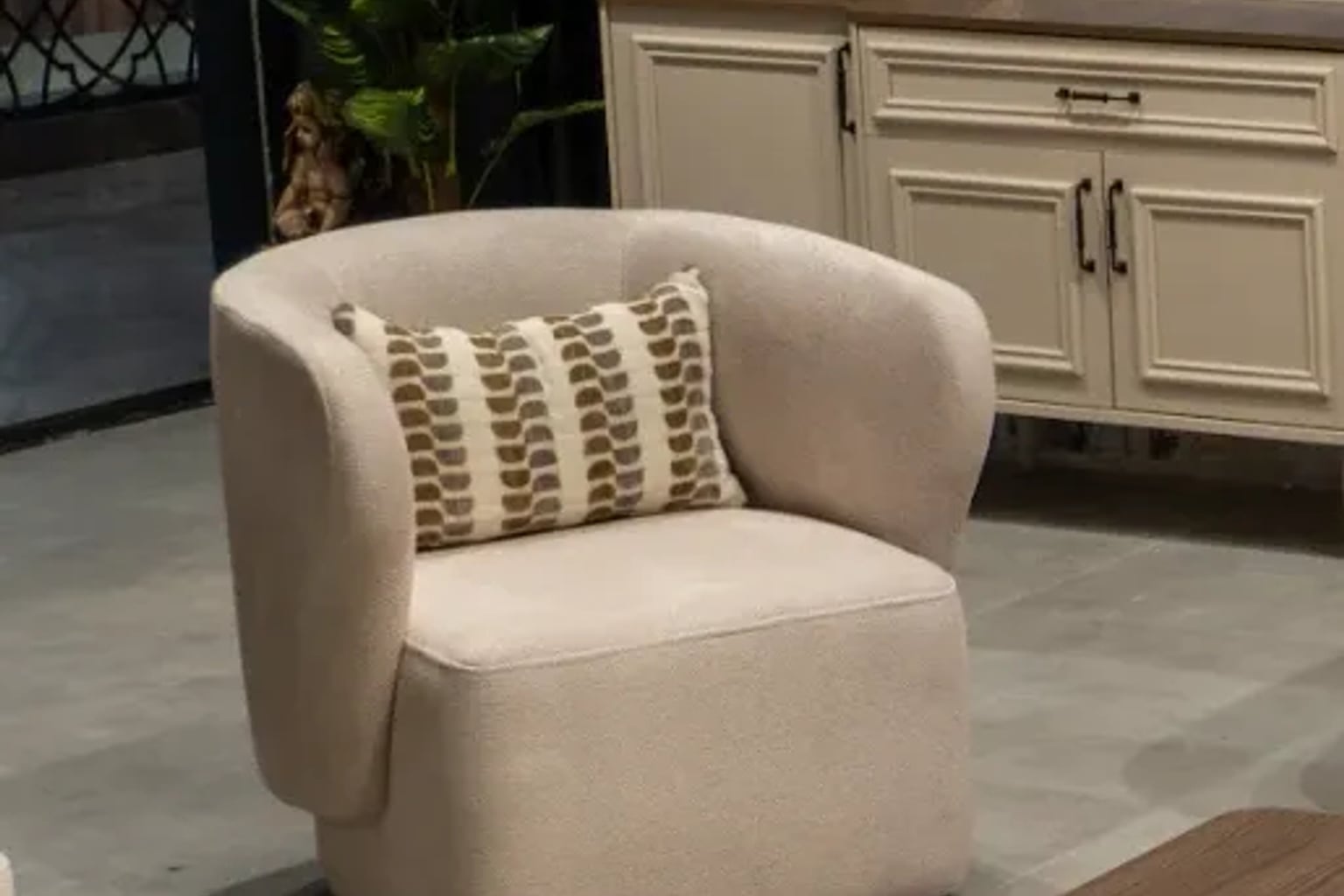 Zarif bir berjer koltuk ve ahşap sehpa ile dekore edilmiş, bej ve krem tonlarında modern bir salon.